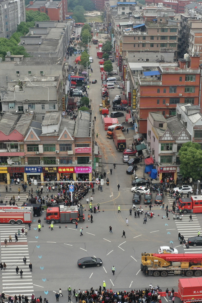 长沙市望城区一栋居民自建房倒塌现场，救援正在进行中。消防等车辆已排成长龙，市民在周围围观。